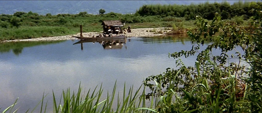 Lone Wolf and Cub: Baby Cart to Hades (1972) movie still: wide — A tranquil river flows past a pebbled shore lined with dense green vegetation. A…