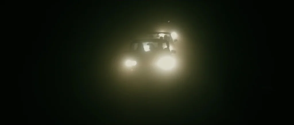 Once Upon a Time in Anatolia (2011) movie still: wide — A dark, unlit road at night is barely visible beyond the reach of headlights. Two vehicles…