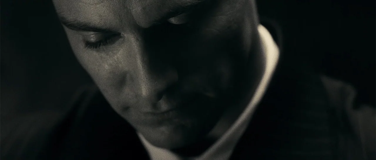 Blood Creek (2009) movie still: closeup — A man's face is illuminated from the side within a completely dark environment. He looks downward with his…