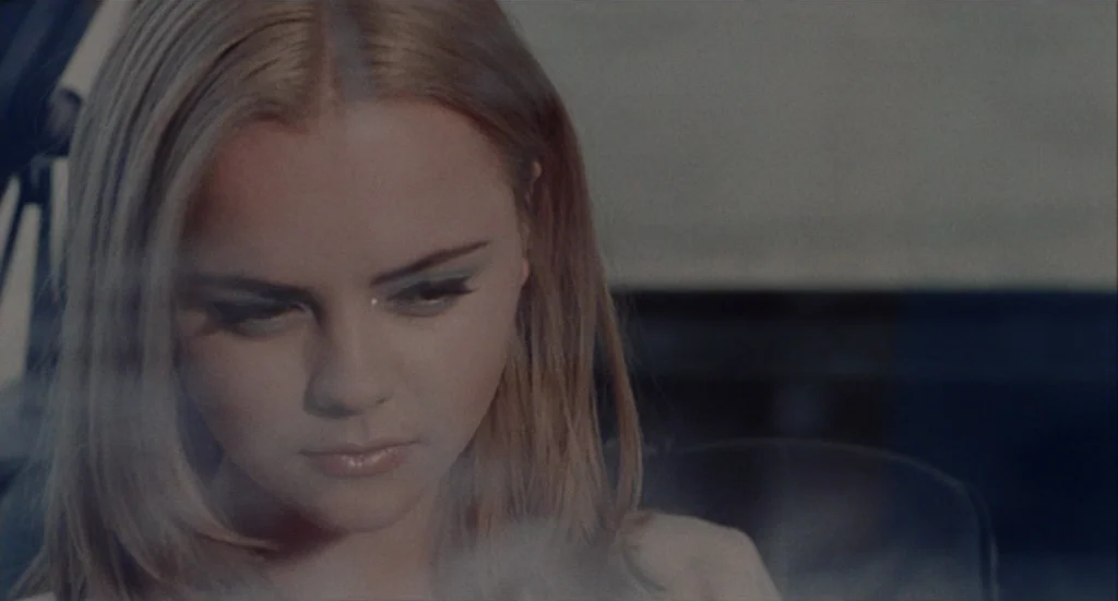 Buffalo ’66 (1998) movie still: closeup — A close-up of a person inside a car with light entering from the side window. A thin plume of cigarette…