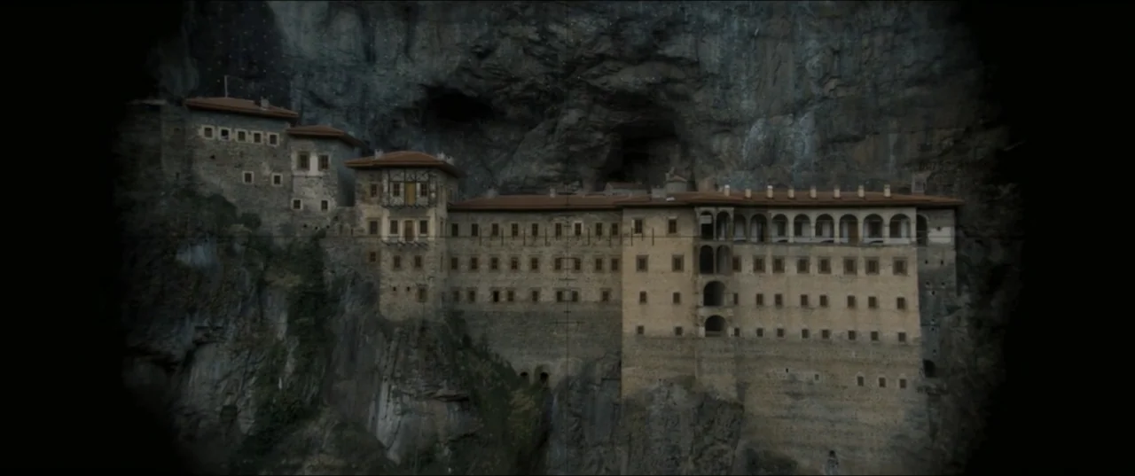 Kraven the Hunter (2024) movie still: establishing — A historic stone monastery is built directly into a steep, rugged mountain cliff face. The…