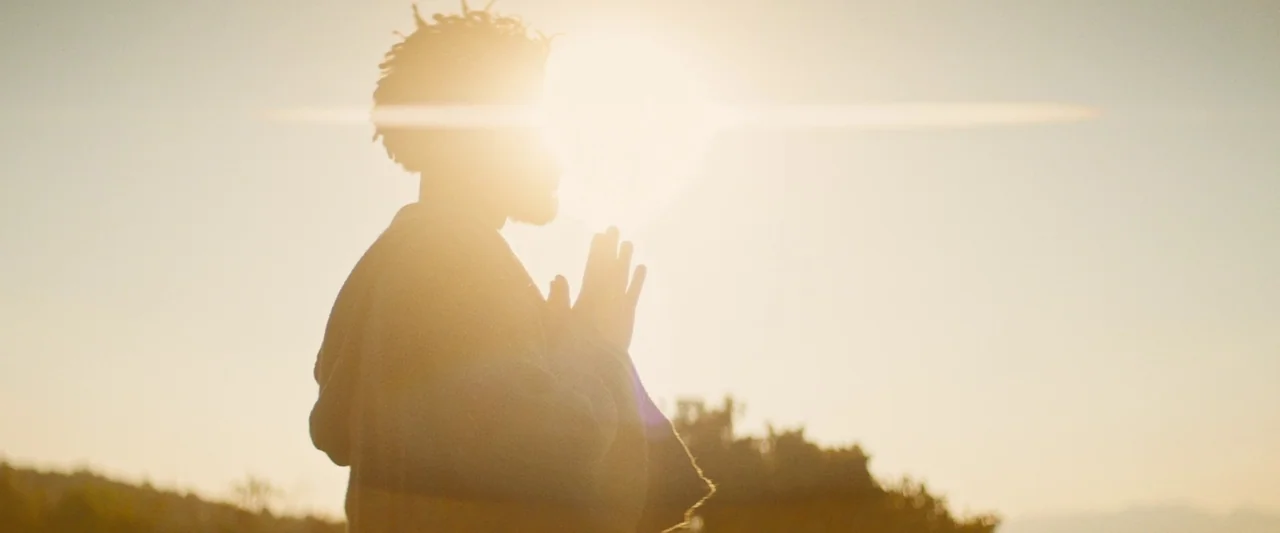 The Book of Clarence (2023) movie still: medium — A field bathed in golden hour light during the late afternoon. A man stands in silhouette with his…