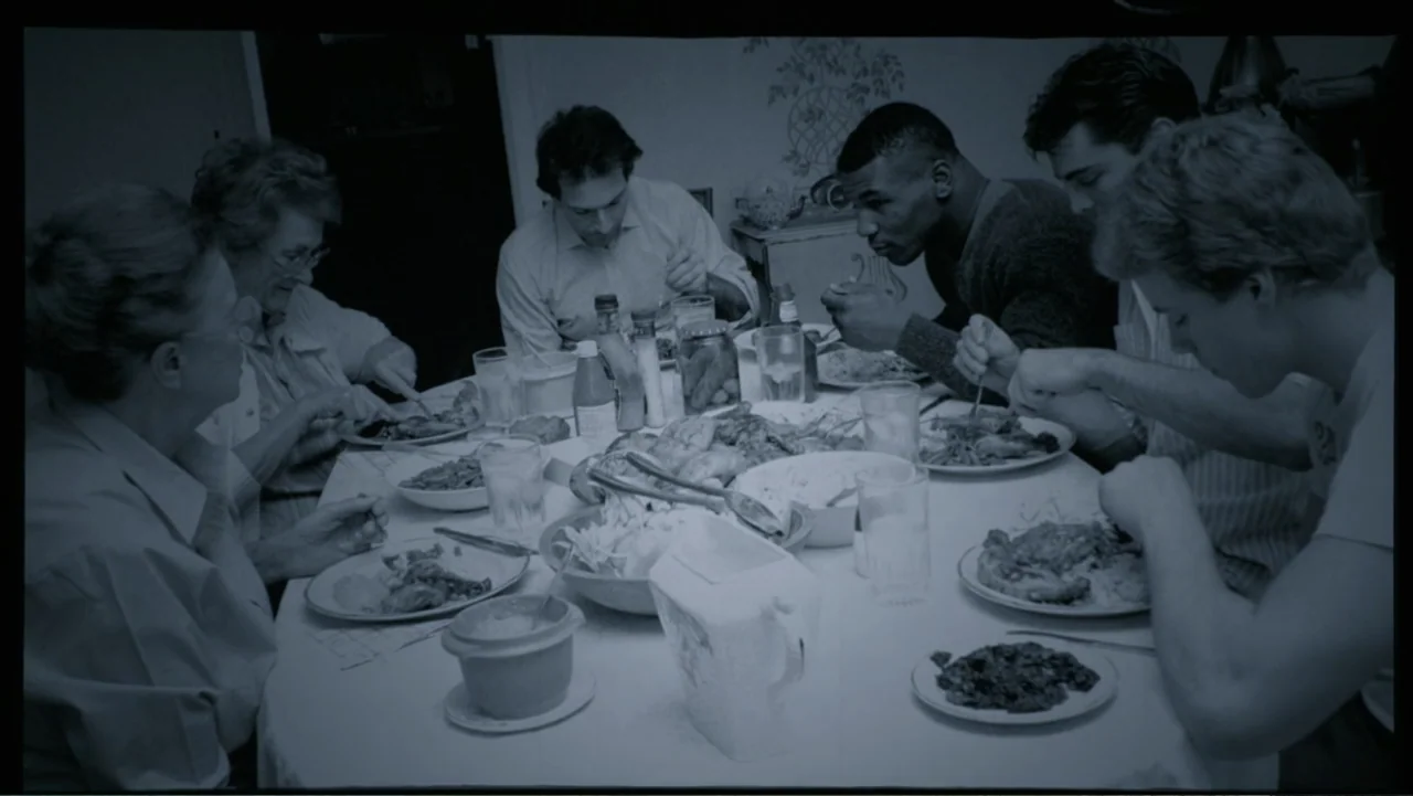 Mike Tyson: Undisputed Truth (2013) movie still: medium — A group of six people sit around a circular table covered with food dishes. The…