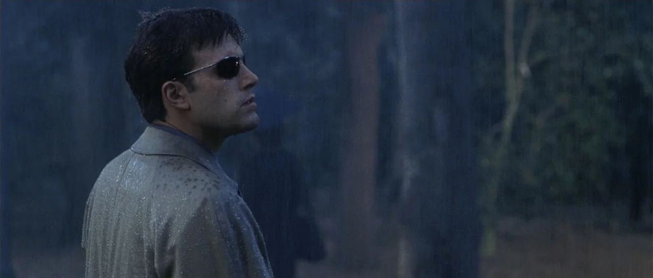 Daredevil (2015) movie still: medium — A dark, rainy woodland setting with dense trees in the background. A man stands in the rain looking off-frame.