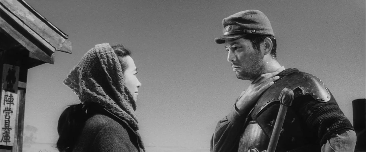 The Human Condition II: Road to Eternity (1959) movie still: medium — An outdoor structure with Japanese text stands behind a woman facing a man.…