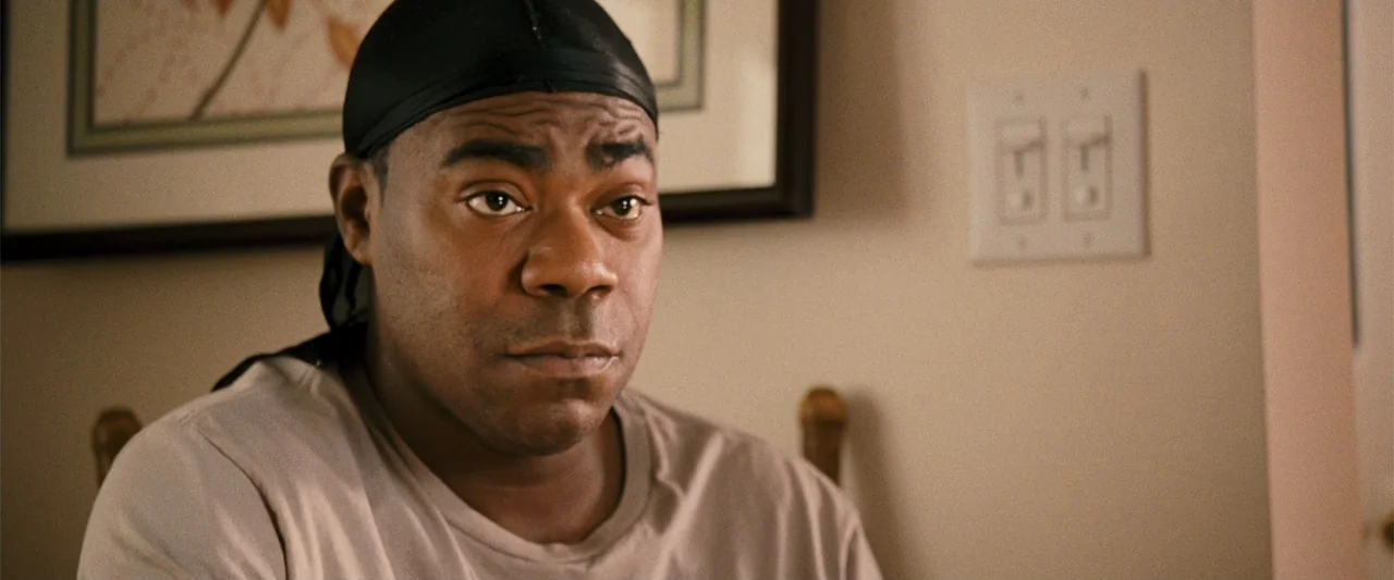 Cop Out (2010) movie still: medium — An interior residential space with a light beige wall featuring a framed picture. A man wearing a black durag…