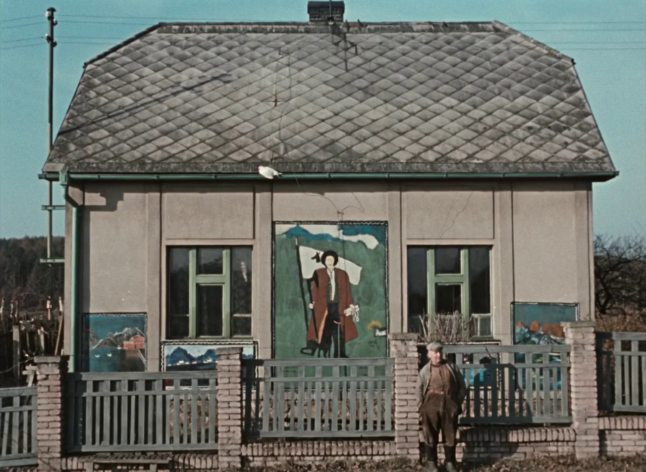 Pearls of the Deep (1965) movie still: wide — A single-story building features diamond-pattern roof tiles and hand-painted folk art murals on walls.…