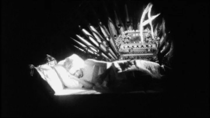 Dracula: Pages from a Virgin’s Diary (2002) movie still: medium — A man lies asleep in a bed with a large musical organ behind him. A glowing symbol…