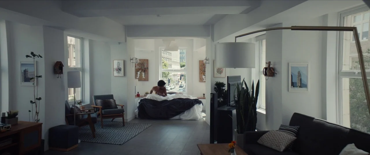 Sorry to Bother You (2018) movie still: wide — A spacious, brightly lit studio apartment features white walls, modern furniture, and large windows.…