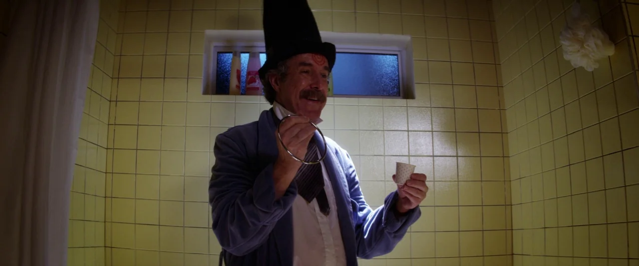 Seven Stages to Achieve Eternal Bliss (2018) movie still: medium — A tiled shower stall features yellow wall tiles and a small rectangular window. A…