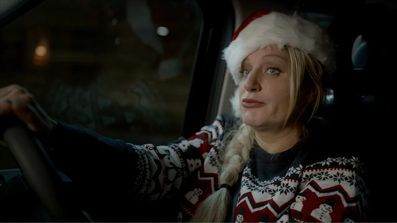 Jack in Time for Christmas (2024) movie still: medium — A dark car interior at night shows a woman behind the steering wheel. She wears a festive…