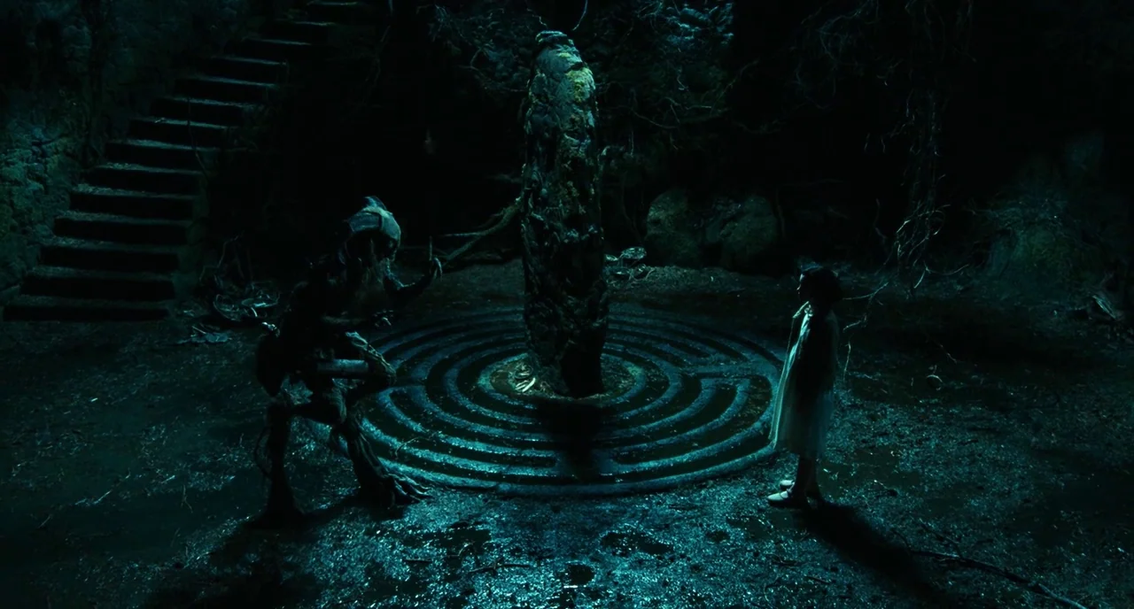 Pan’s Labyrinth (2006) movie still: wide — A dark subterranean stone chamber contains a central spiraling pattern carved into the floor. A faun-like…