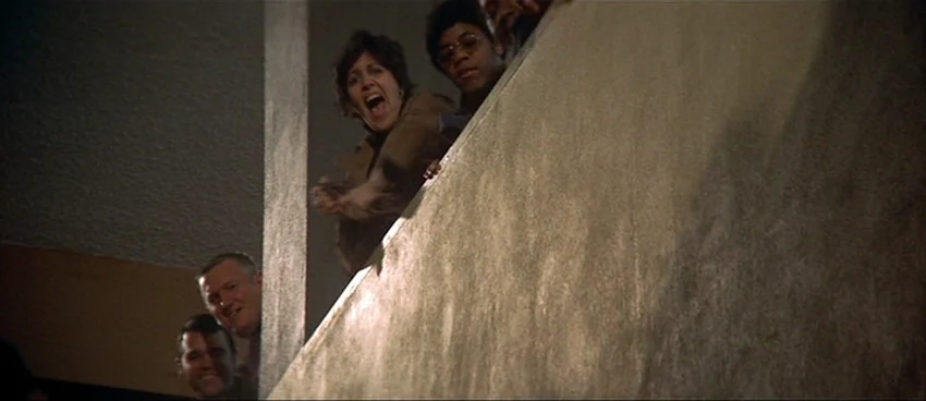 California Split (1974) movie still: medium — Several people stand on a concrete ledge looking down at an unseen event. The lighting creates strong…
