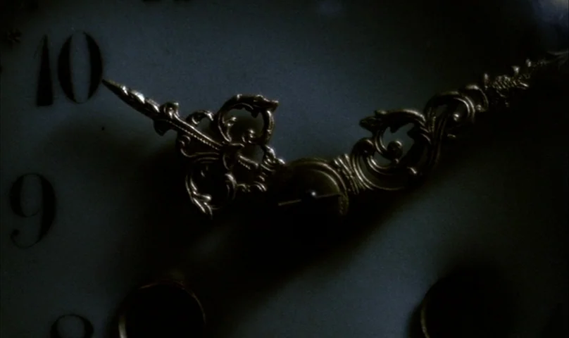 Cries and Whispers (1972) movie still: closeup — A close view of an antique clock face with ornate, dark metal hands. The numerals nine and ten are…