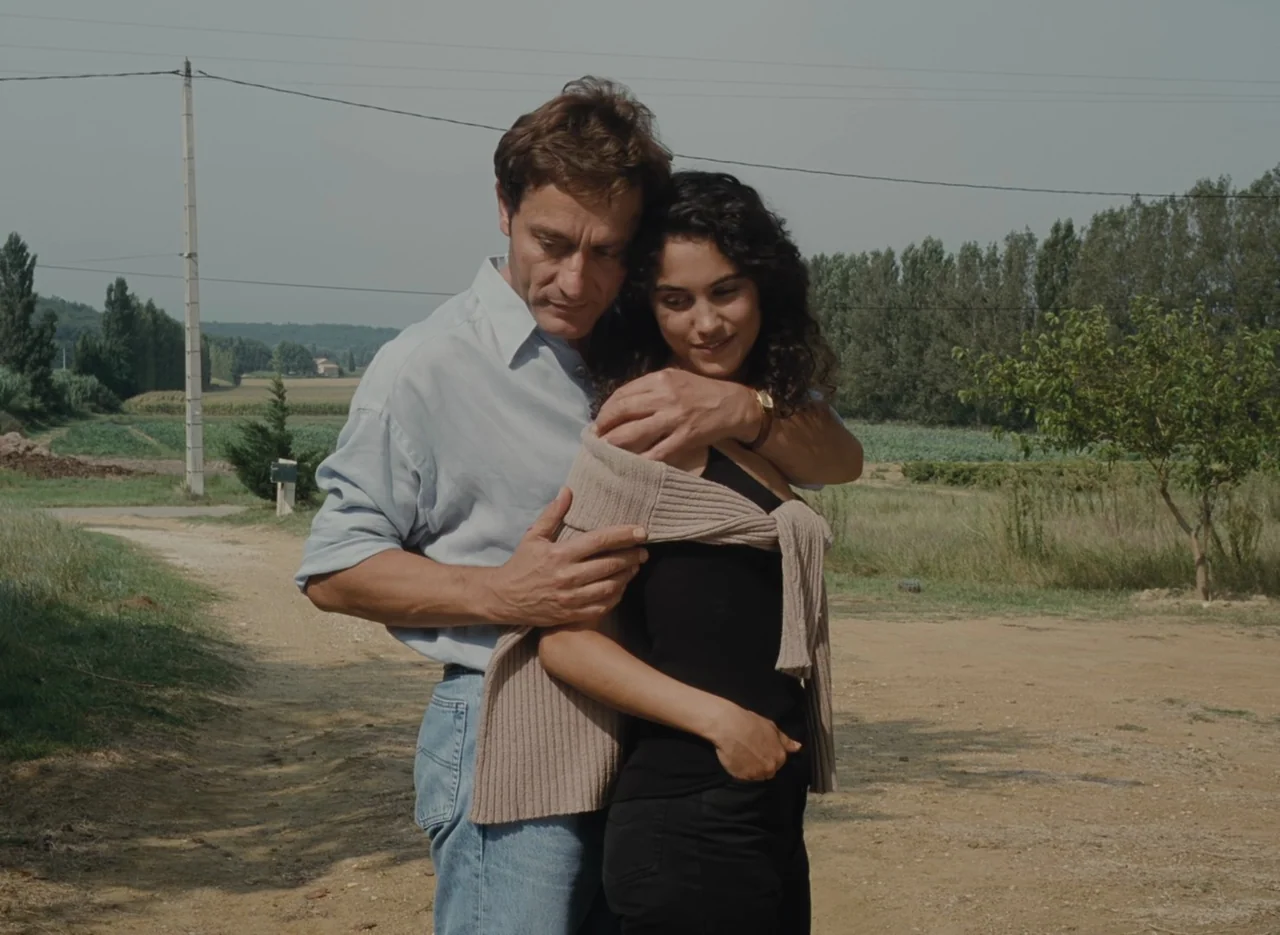 Autumn Tale (1998) movie still: medium — A man and woman stand together on a dry rural dirt road in daylight. They are positioned facing the camera…
