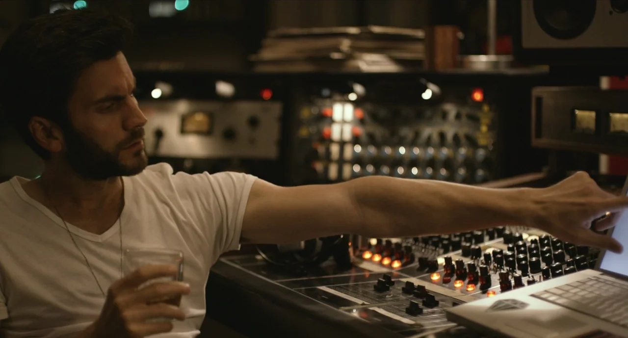 We Are Your Friends (2015) movie still: medium — A recording studio interior features rows of analog audio equipment and a laptop screen. A man sits…