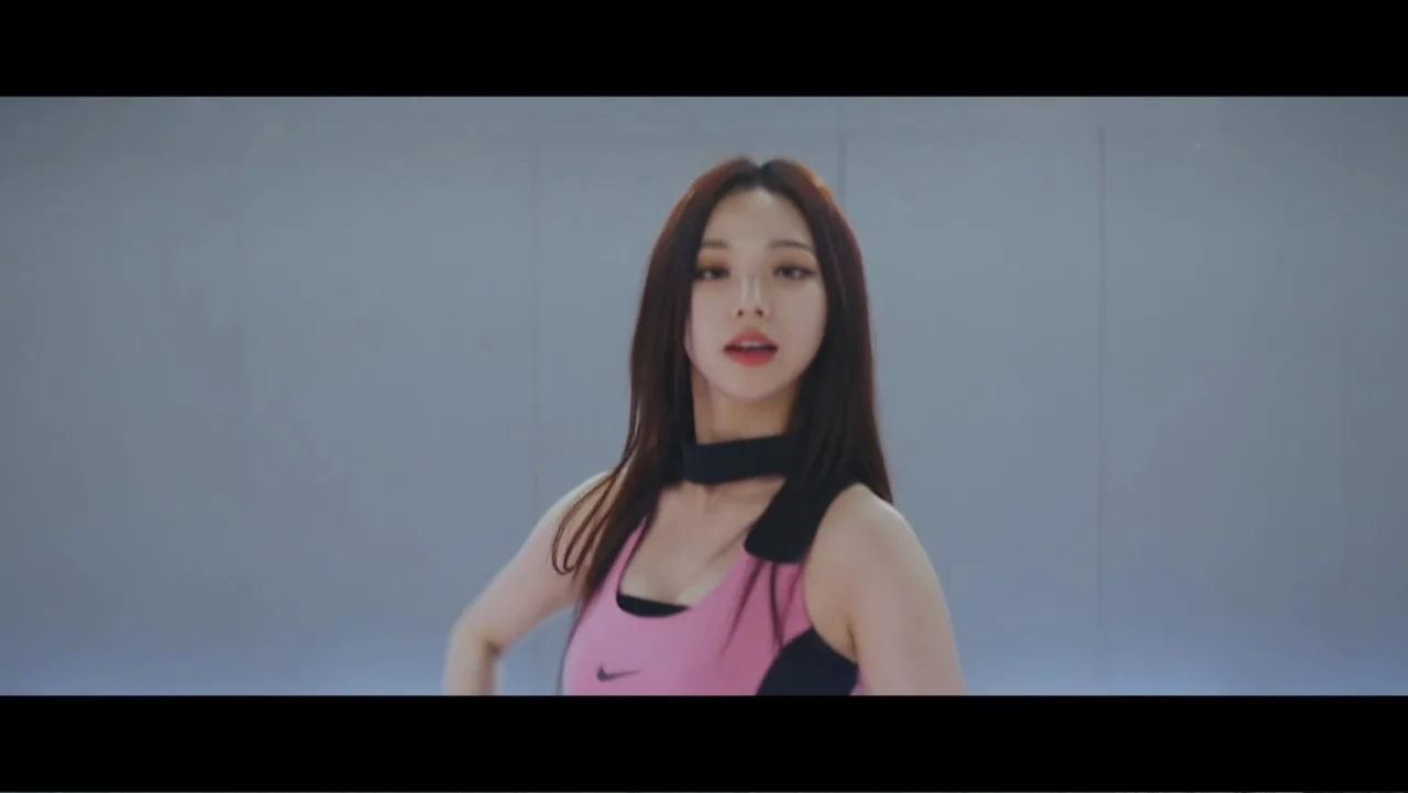 Lee Soo Man: King of K-Pop (2025) movie still: medium — A minimalist studio space features a smooth, light grey wall as a backdrop. A young woman in…