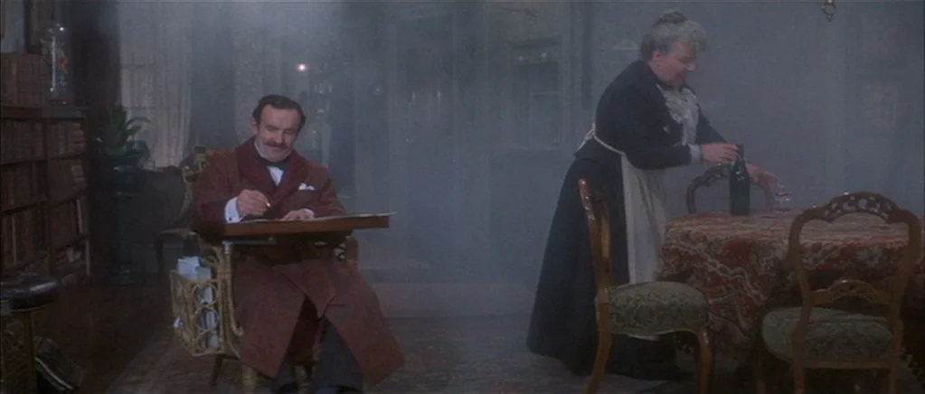 The Private Life of Sherlock Holmes movie still: wide — A smoke-filled Victorian interior features a man writing at a desk and a maid. The woman…
