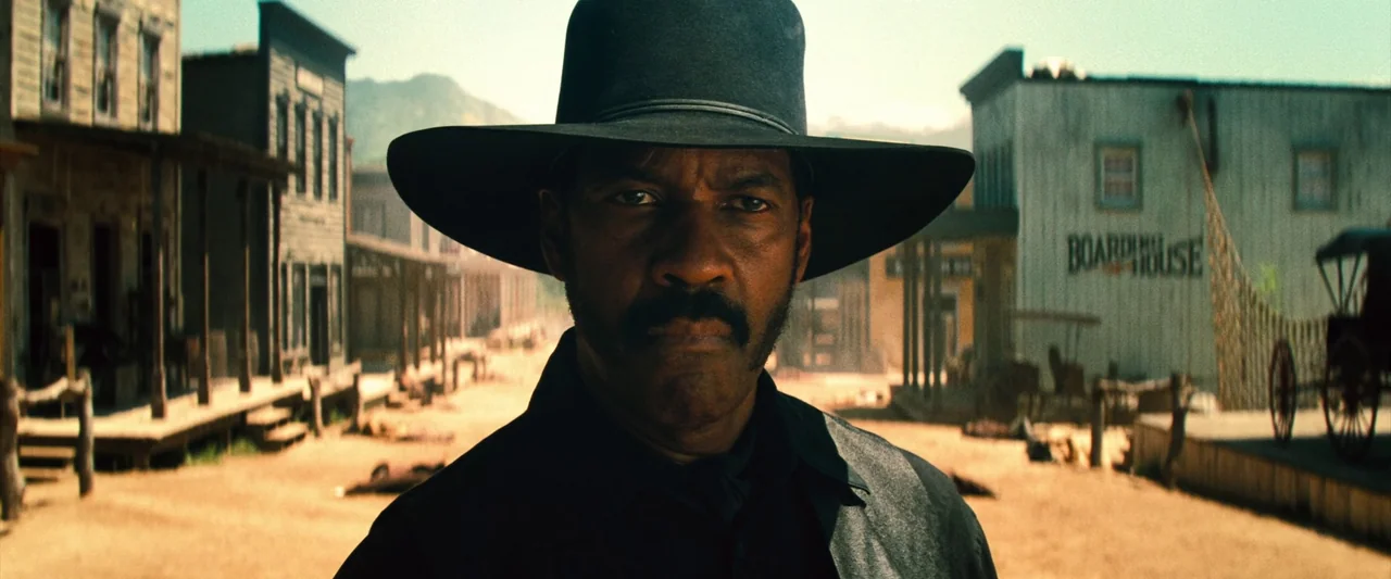 The Magnificent Seven (2016) (2016) movie still: medium — A dusty main street of a historic western frontier town with wooden buildings. A man…