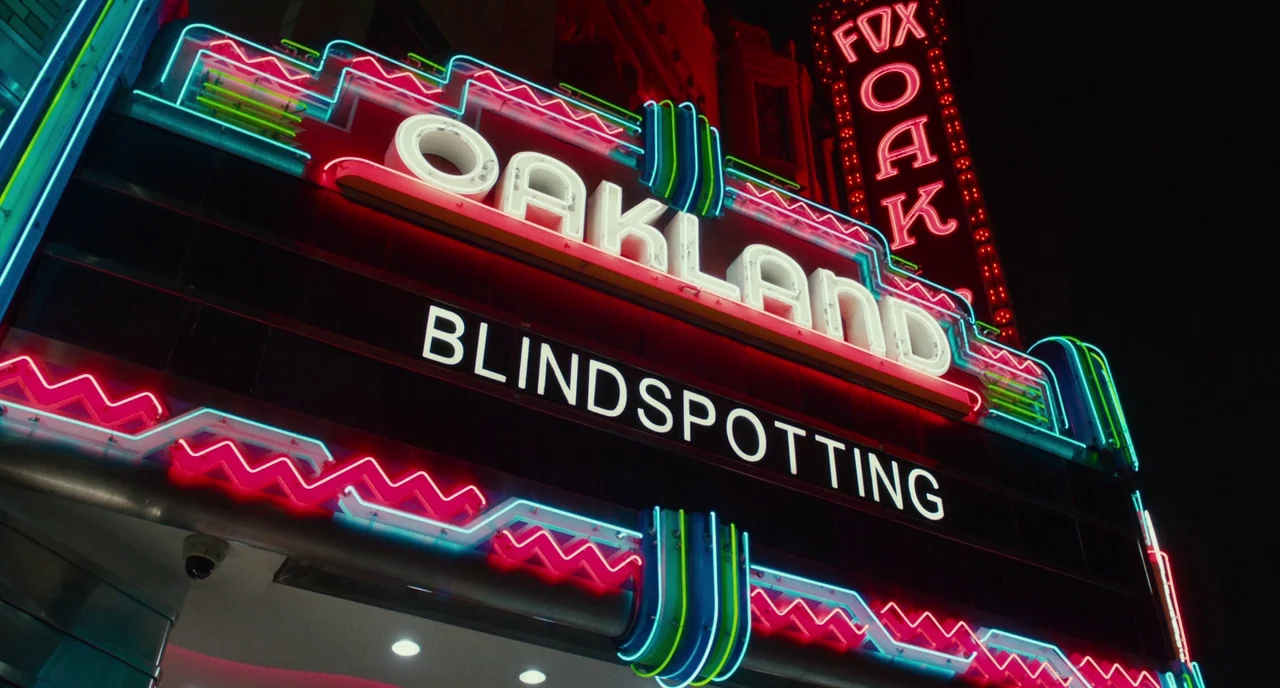 Blindspotting (2018) movie still: wide — The neon-lit exterior marquee of the Fox Oakland theater at night. The sign displays the name of the…