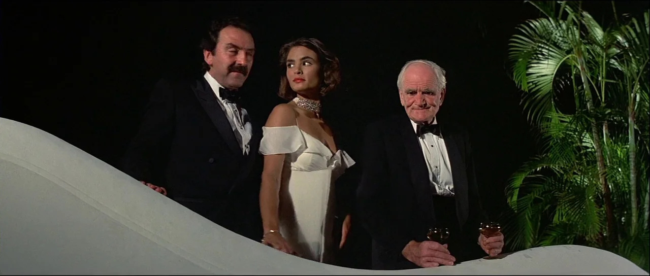 Licence to Kill (1989) movie still: medium — Three people in formal attire stand on a terrace at night against black darkness. The man on the right…