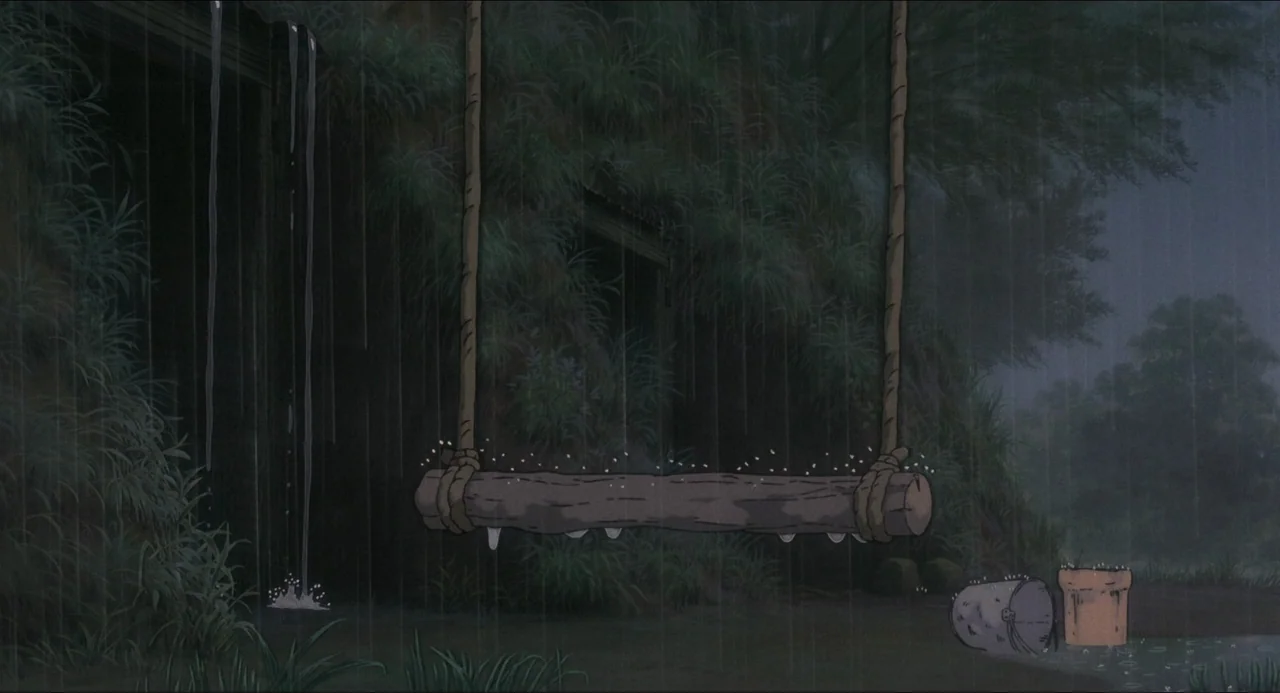 Grave of the Fireflies (1988) movie still: wide — A rural landscape at night features an empty wooden swing suspended during heavy rain. Thick…