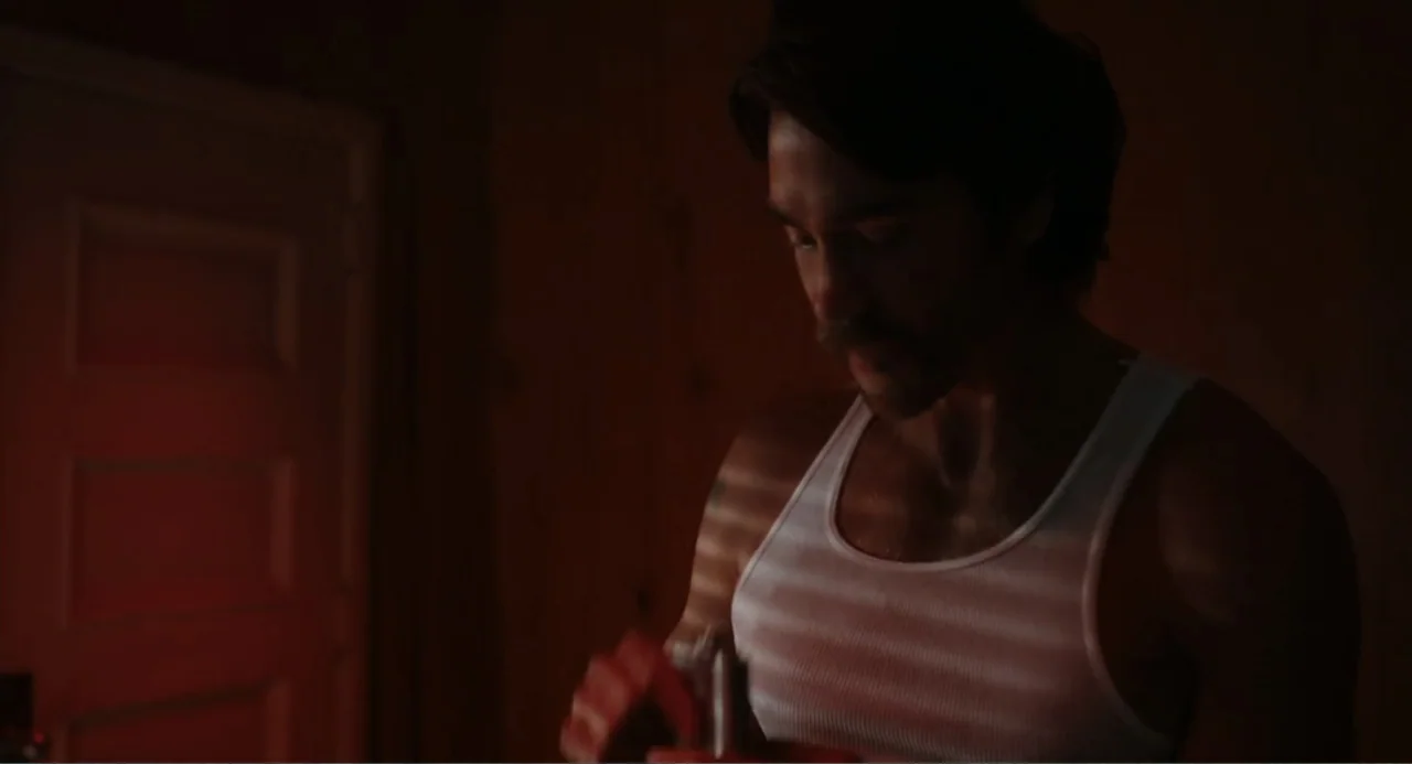 Ted Bundy: American Boogeyman (2021) movie still: medium — A dimly lit room features wood-paneled walls and a single closed white door. A man in a…