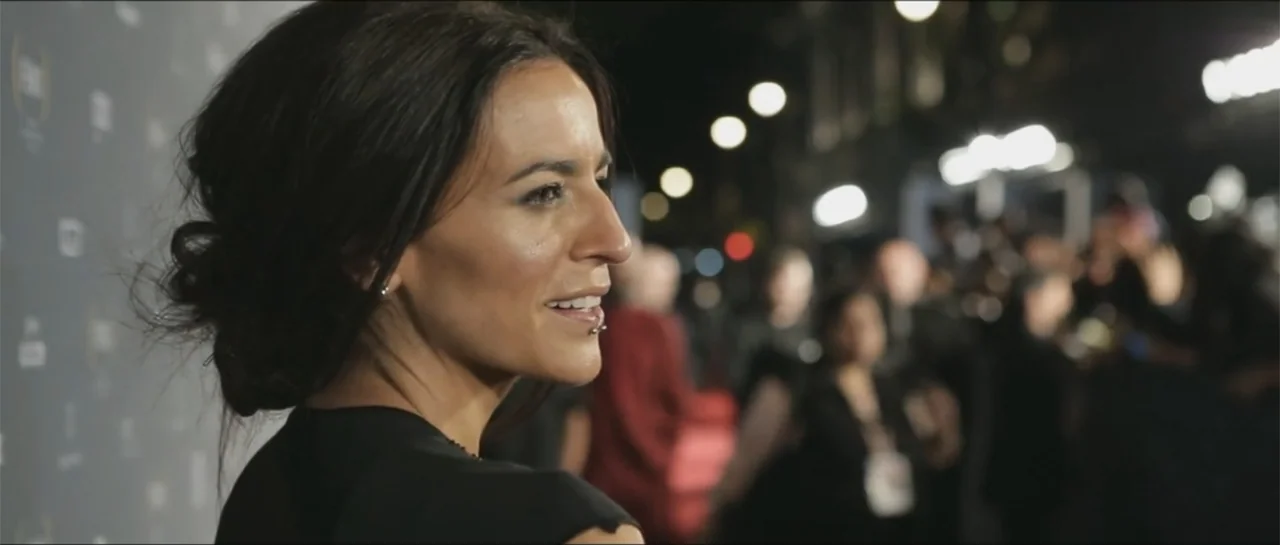 10 Years with Bebe (2016) movie still: medium — A woman stands on a red carpet at night with a blurred press line behind. She glances to the side…