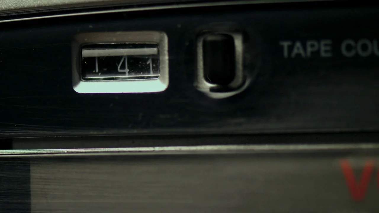 The Pact II movie still: closeup — A close-up view of a black metal vintage audio cassette player tape counter. The digits 141 are visible inside a…