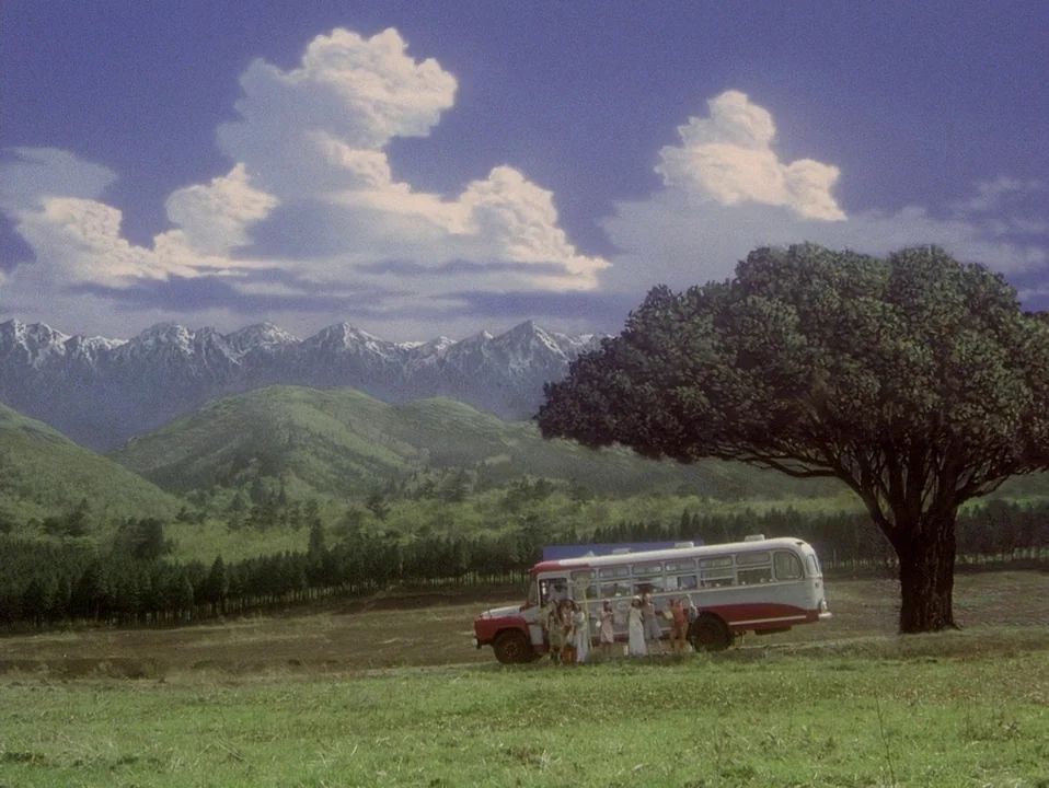 House (Hausu) (1977) movie still: wide — A rural landscape features a large tree next to a parked bus. A group of people stands by the vehicle in…