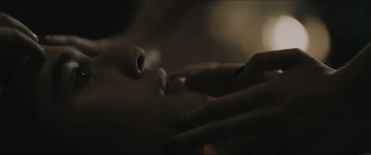 Death to Summer (2021) movie still: closeup — A darkened interior space shows only the upper portion of a face in profile. A hand reaches into the…