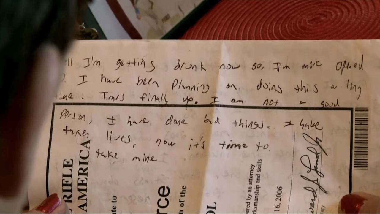 Wartorn: 1861-2010 (2010) movie still: closeup — A close-up view of a handwritten suicide note placed on a table surface. A thumb with red nail…