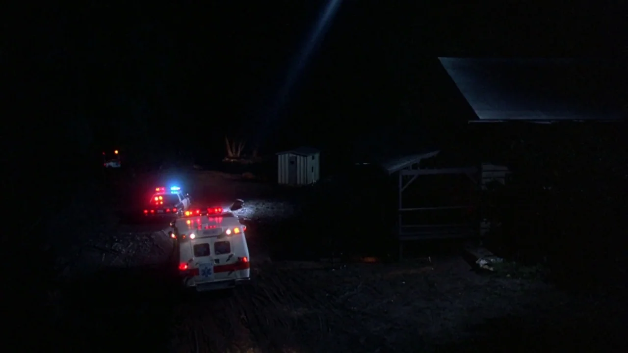 Friday the 13th: The Final Chapter (1984) movie still: establishing — A dark, unpaved rural lot features an ambulance and a police cruiser at night.…