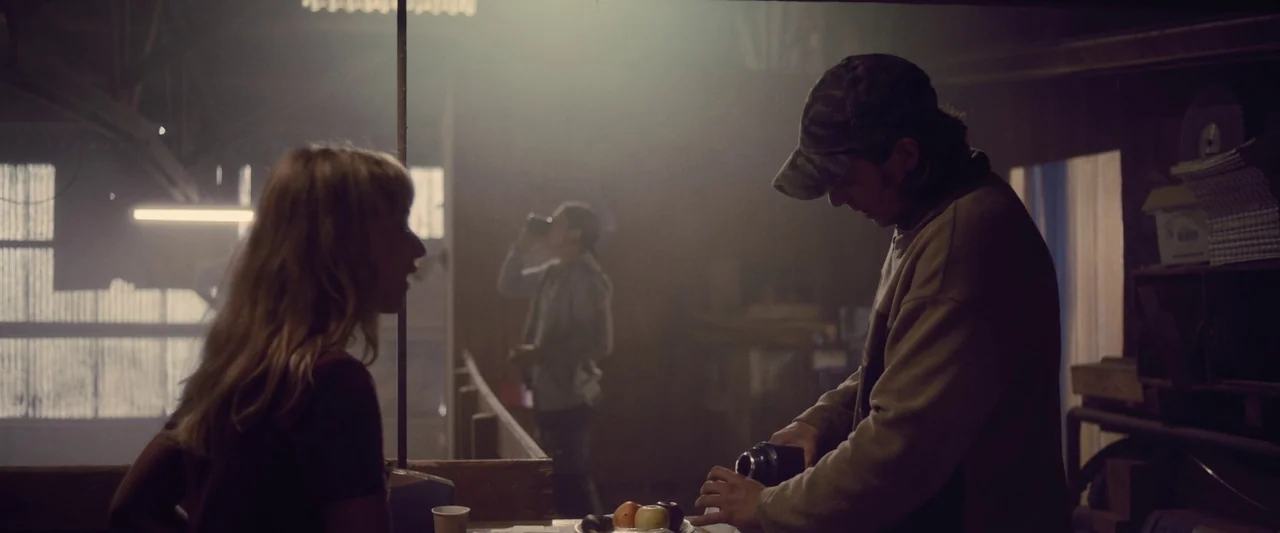 Meanwhile On Earth (2024) movie still: medium — A cluttered workshop space filled with dust and light beams filtering through the air. A man in a…
