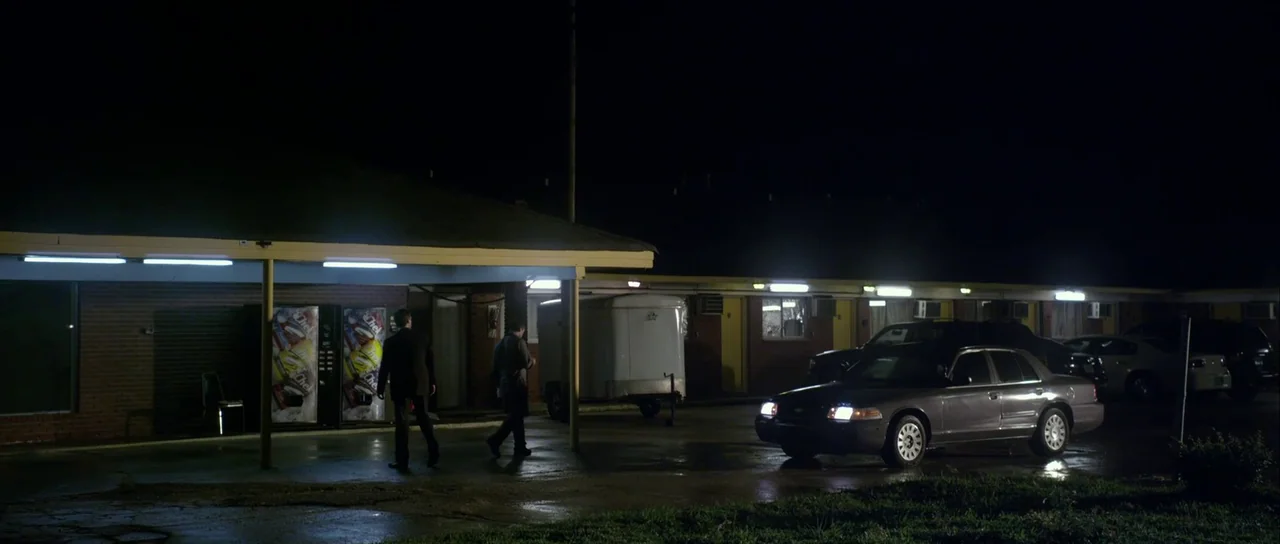 Universal Soldier: Day of Reckoning (2012) movie still: wide — A dark, multi-unit single-story motel complex is illuminated by bright overhead…