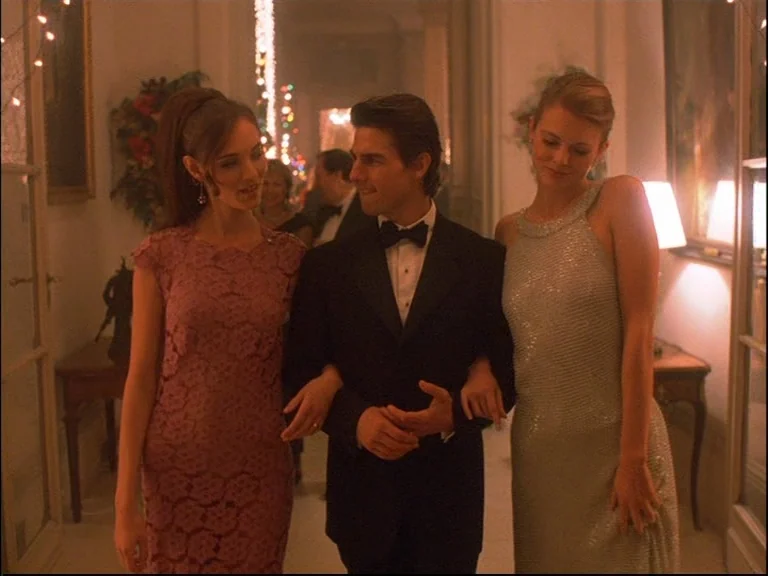 Eyes Wide Shut (1999) movie still: medium — A well-lit residential hallway decorated for a social event with draped fairy lights. A man walks…