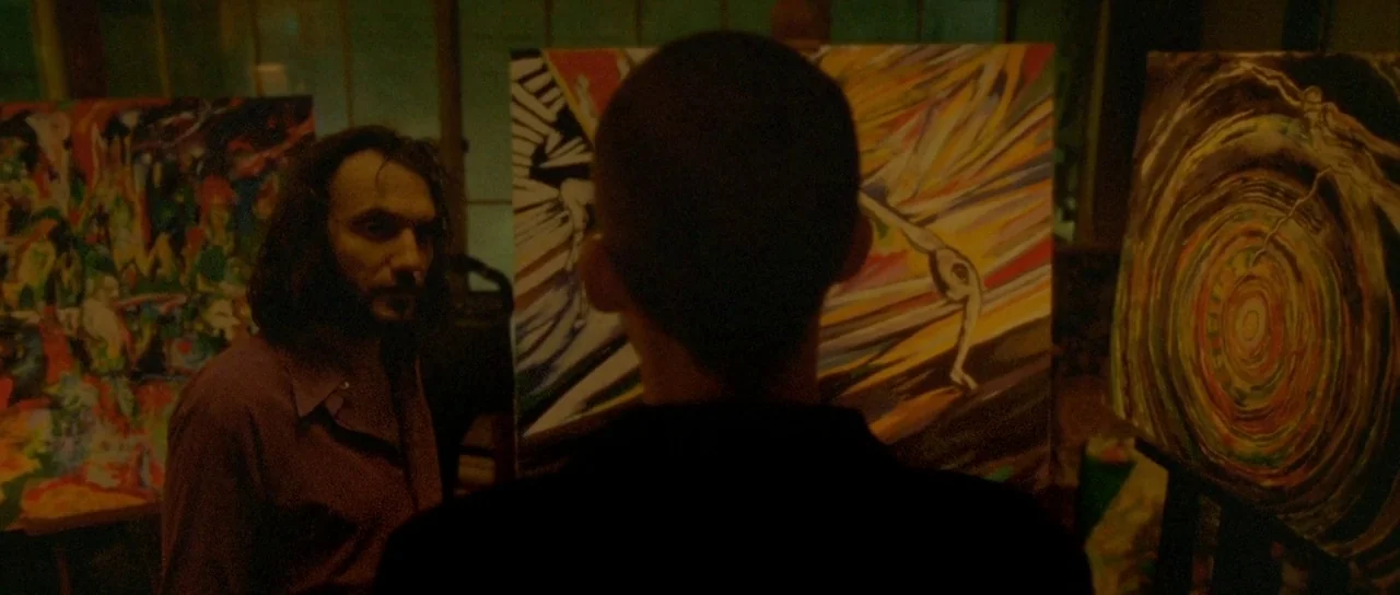 Enter The Void (2009) movie still: medium — A dimly lit room filled with vibrant, expressive paintings on wooden easels. One man stands by a…