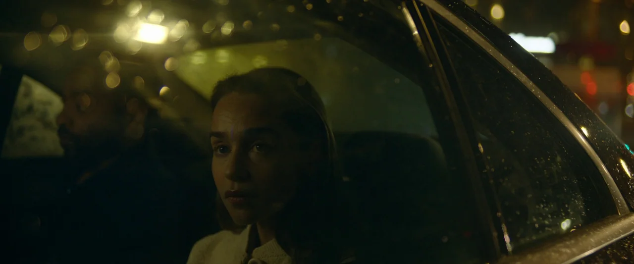 The Pod Generation (2023) movie still: medium — The interior of a car at night during rainfall with city lights blurred outside. A woman sits in the…
