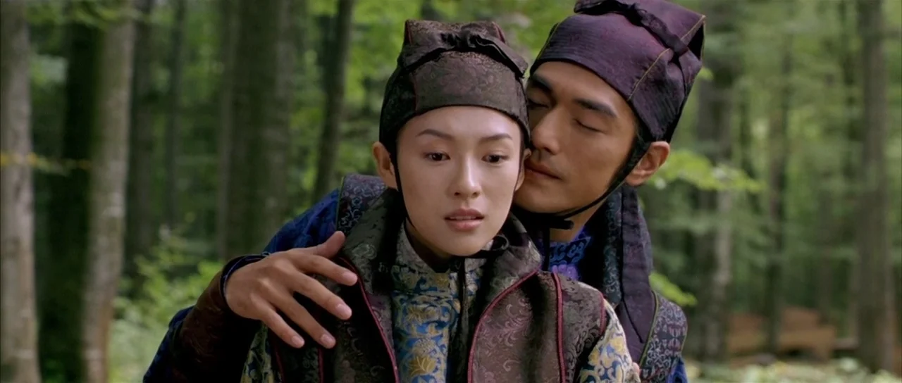 House of Flying Daggers (2004) movie still: medium — A man and woman dressed in traditional historical clothing stand within a dense forest. The man…