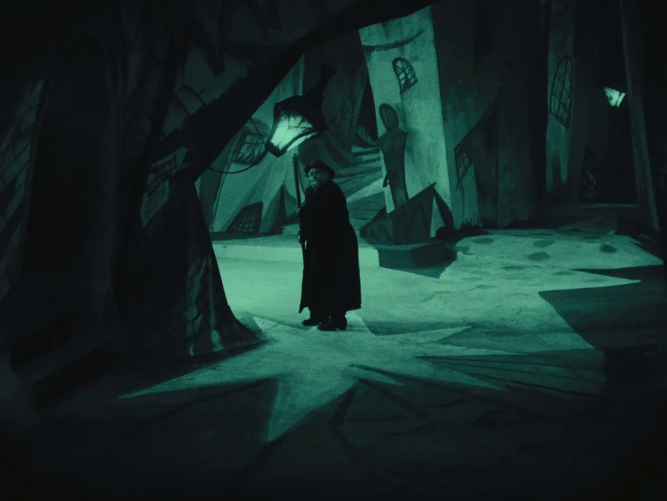 The Cabinet of Dr. Caligari (1920) movie still: wide — A stylized German Expressionist city set features distorted buildings painted on flat…