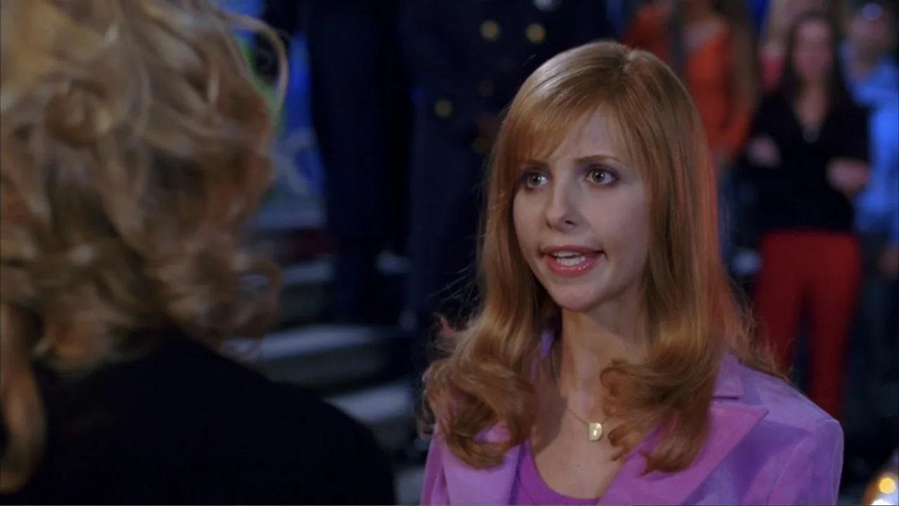 Scooby-Doo 2: Monsters Unleashed (2004) movie still: medium — An indoor school corridor features a blurred crowd standing in the background. A young…
