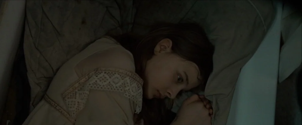 Let Me In (2010) movie still: closeup — A porcelain bathtub interior lined with a plain, light gray fabric cloth. A young woman in a lace-trimmed…