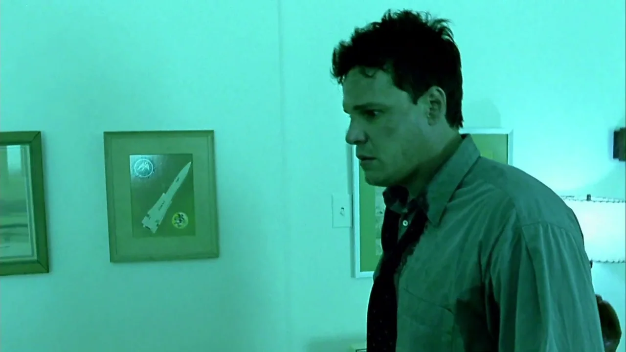 Hellraiser: Inferno (2000) movie still: medium — A plain interior wall features framed artwork alongside a light switch plate. A man stands in the…