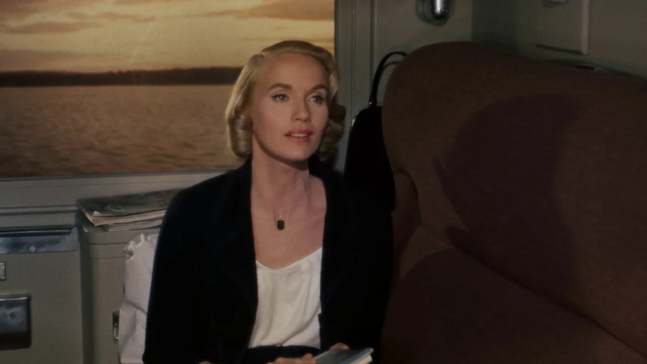 North By Northwest (1959) movie still: medium — A passenger seat inside a train carriage during the late evening. A blonde woman sits against the…
