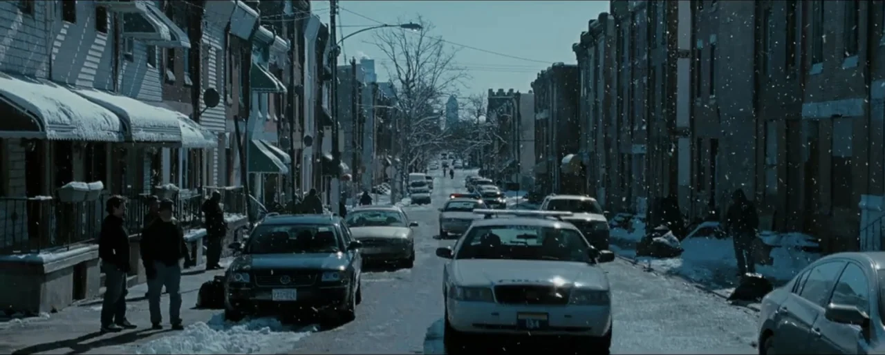 Law Abiding Citizen (2009) movie still: wide — A residential street lined with brick row houses is covered in light snow. Two police cruisers slowly…