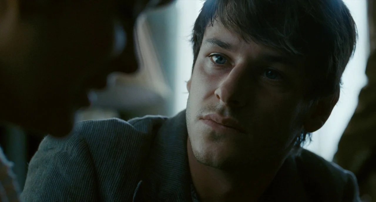 It’s Only The End Of The World (2016) movie still: closeup — An interior space with cool lighting tones reflecting off the man's skin. A man with…