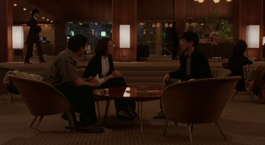 Yi-Yi (A One and A Two) (2000) movie still: wide — A dark hotel lobby features wood-paneled walls and minimalist fabric-covered furniture. Three…