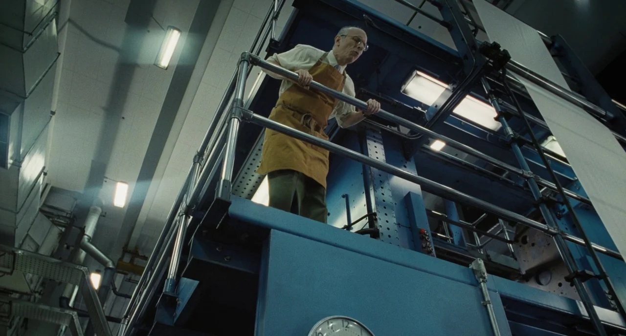 The Post (2017) movie still: fullbody — A high-ceilinged industrial factory floor with massive blue printing equipment and metallic catwalks. A…