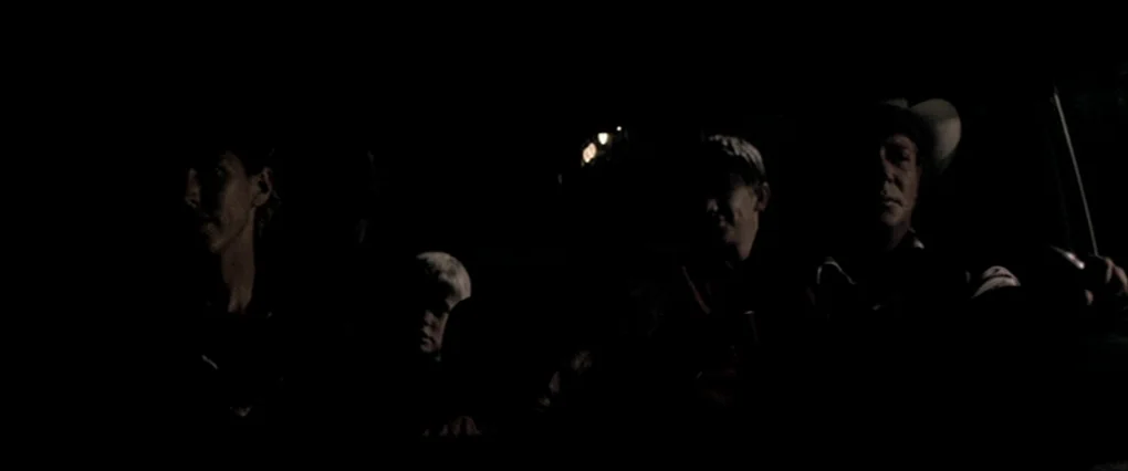 Silent Light (2007) movie still: medium — A dark, cramped interior of a vehicle at night with four passengers sitting together. The occupants look…