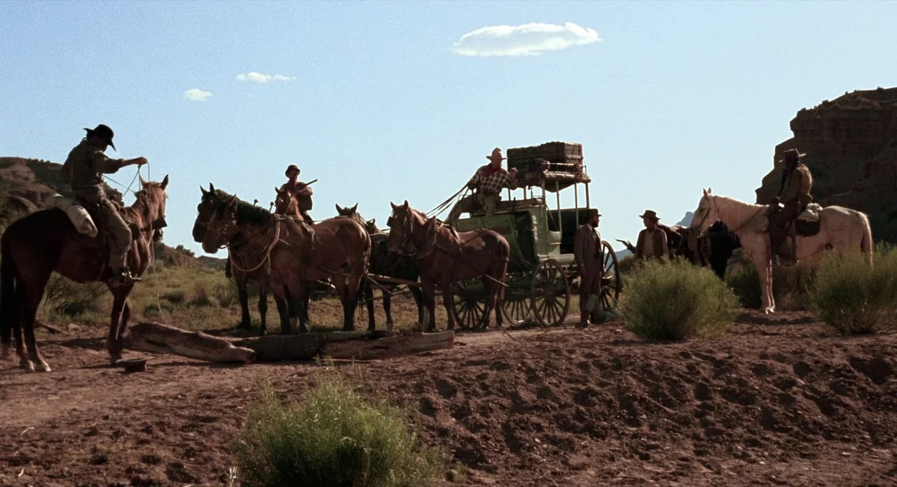 Ride In The Whirlwind (1966) movie still: wide — A rugged desert landscape features a horse-drawn stagecoach and several men on horseback. The group…